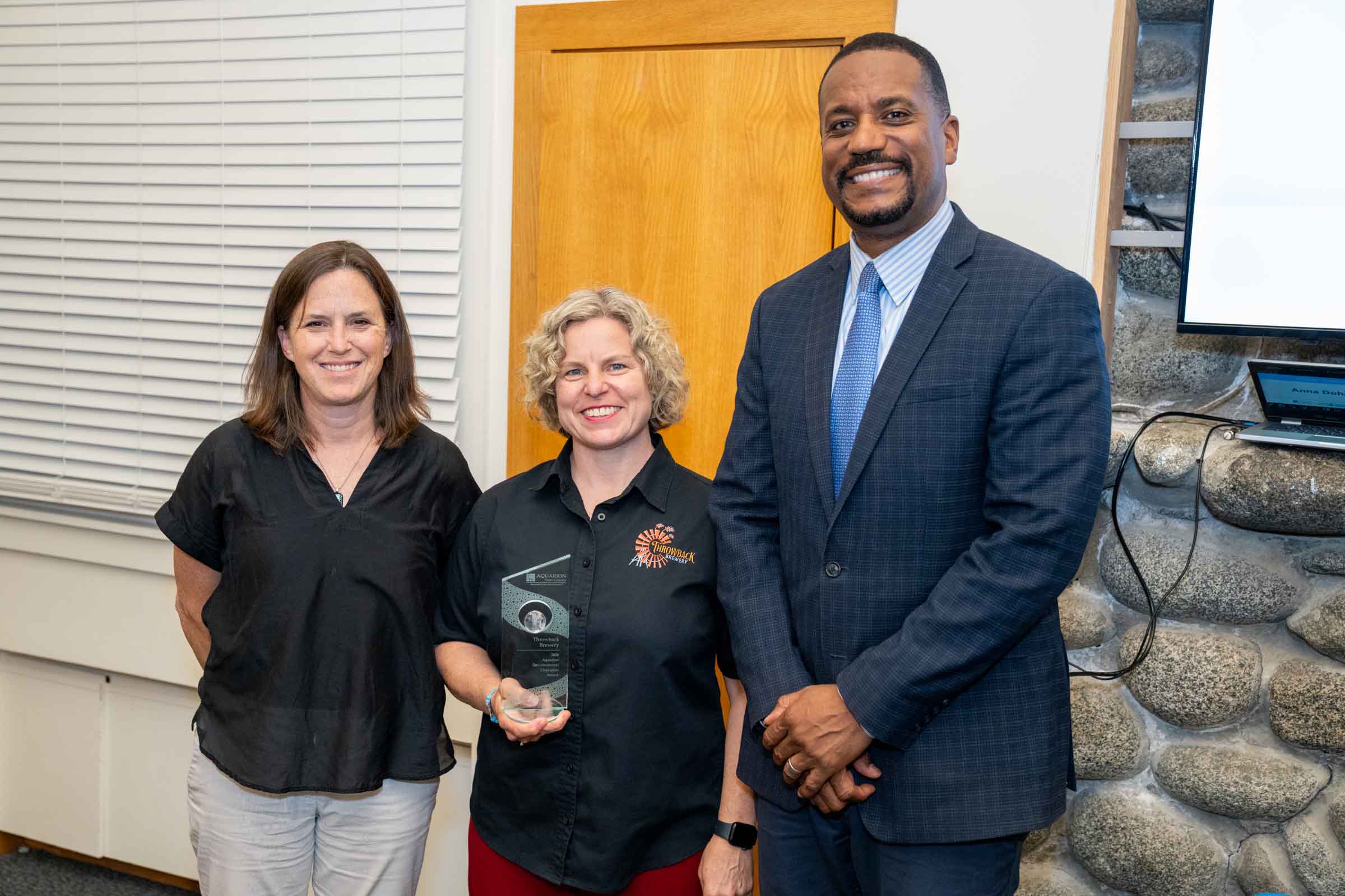 Nicole Carrier, co-founder and president of Throwback Brewery poses with her award. Next to her are Jen Kennedy of Blue Ocean Society and George Logan of Aquarion.