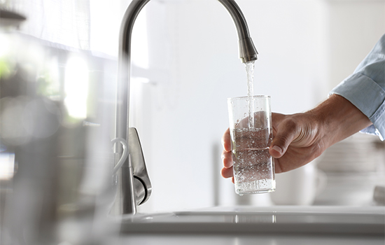 person filling up a glass of tap water